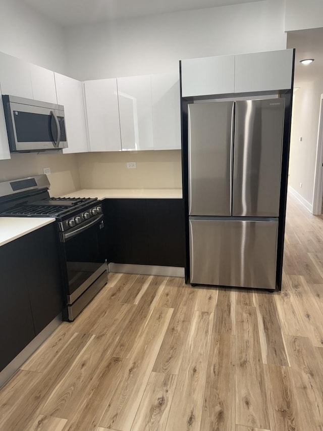 kitchen with white cabinetry, light wood-type flooring, modern cabinets, and appliances with stainless steel finishes