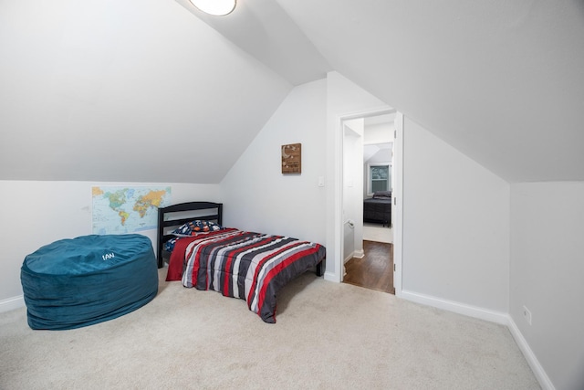carpeted bedroom with baseboards and vaulted ceiling