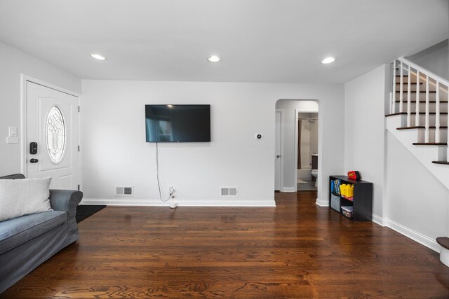 living area featuring stairs, arched walkways, visible vents, and wood finished floors