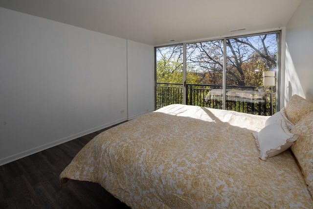 bedroom featuring baseboards, visible vents, wood finished floors, and multiple windows