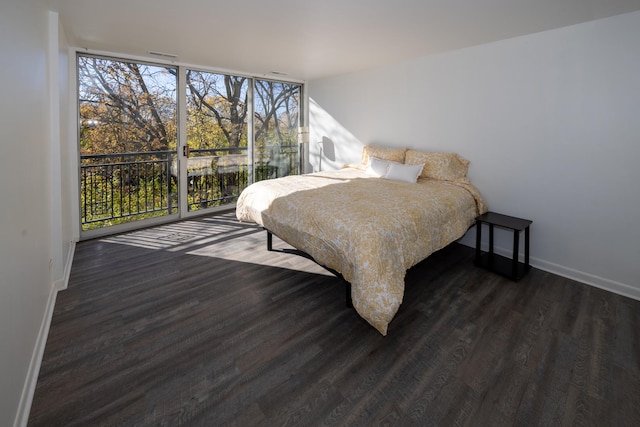 bedroom featuring wood finished floors, a wall of windows, and multiple windows