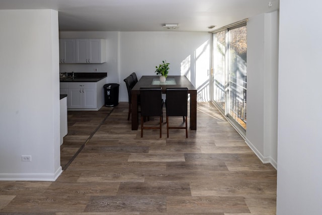 dining area featuring baseboards, wood finished floors, and floor to ceiling windows