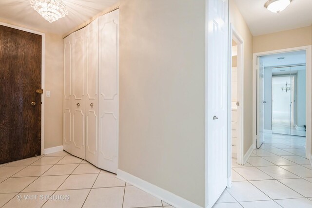 unfurnished living room with baseboards, a chandelier, light tile patterned floors, and visible vents