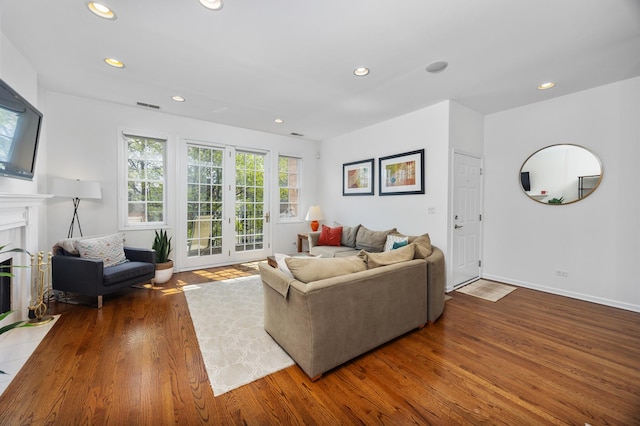 living area with a fireplace with flush hearth, recessed lighting, wood finished floors, and visible vents