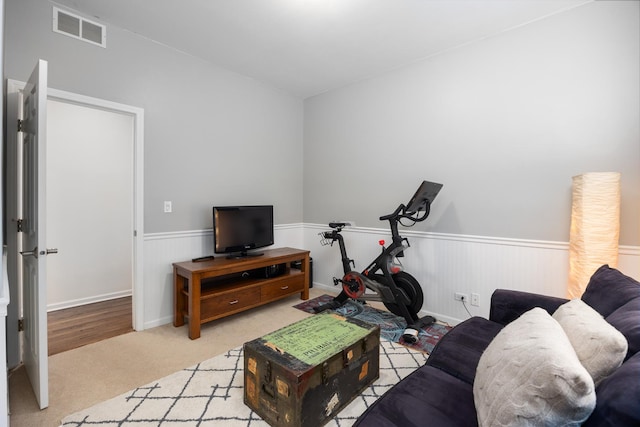carpeted living area featuring visible vents and a wainscoted wall