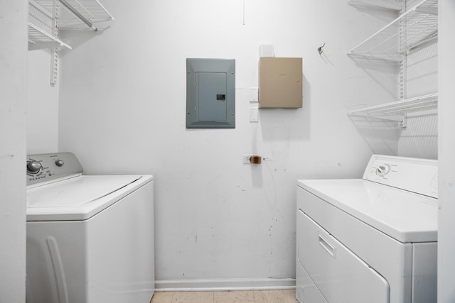 washroom featuring laundry area, baseboards, electric panel, and washing machine and clothes dryer