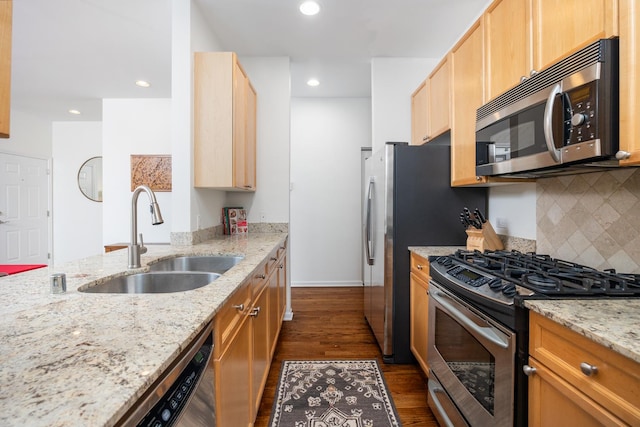 kitchen featuring dark wood-style floors, light stone counters, a sink, backsplash, and stainless steel appliances