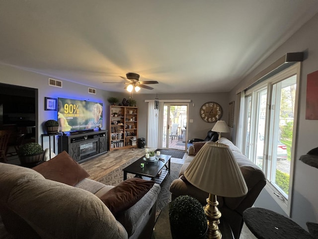 living room featuring visible vents, ceiling fan, wood finished floors, and a wealth of natural light