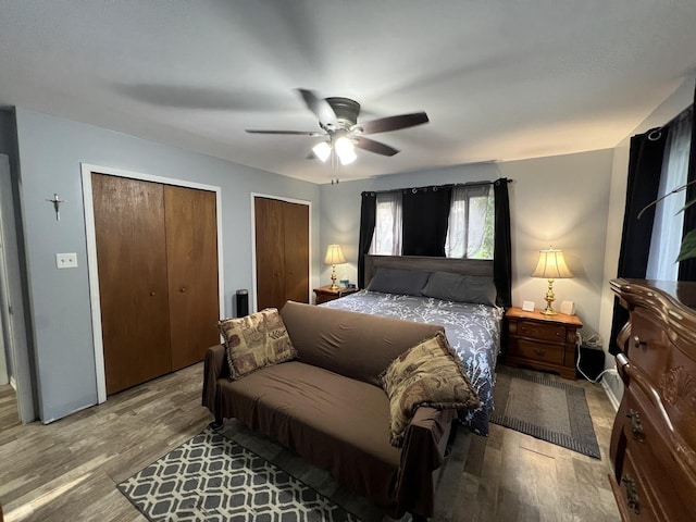 bedroom featuring wood finished floors, ceiling fan, and two closets