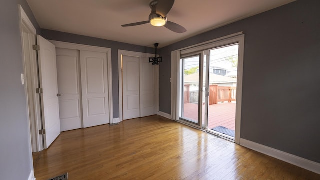 unfurnished bedroom with two closets, baseboards, access to outside, and light wood-style floors
