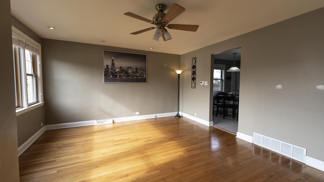 empty room with a ceiling fan, visible vents, and wood finished floors
