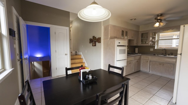 dining space featuring light tile patterned floors, a ceiling fan, and stairs