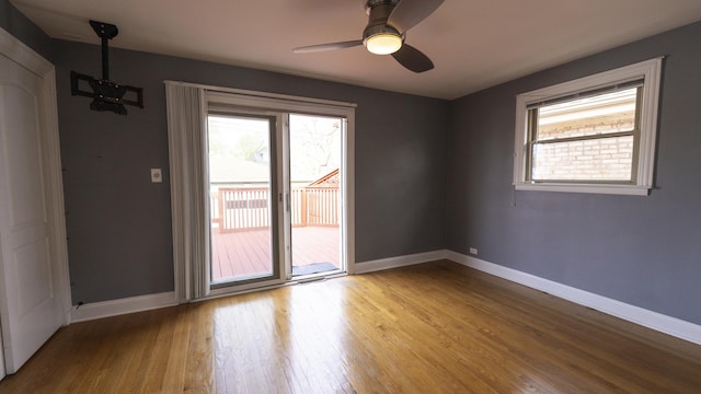 empty room with baseboards, wood finished floors, a healthy amount of sunlight, and ceiling fan