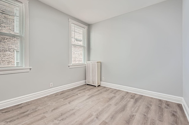 unfurnished room featuring baseboards, wood finished floors, and a healthy amount of sunlight