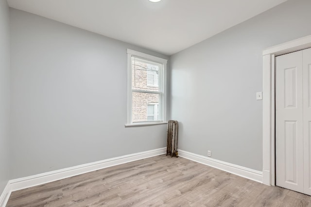 spare room with light wood-type flooring, vaulted ceiling, and baseboards