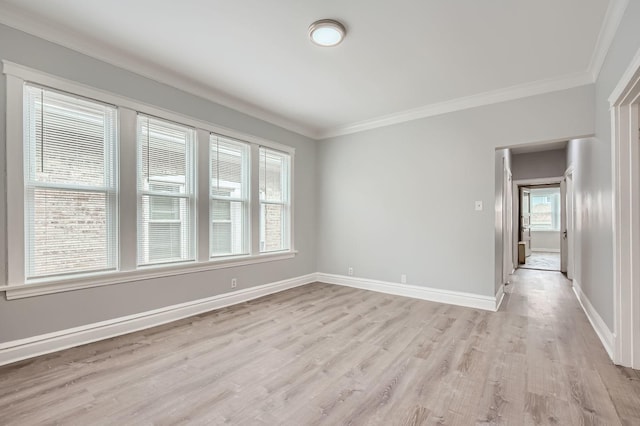 unfurnished room with baseboards, ornamental molding, and light wood-style floors