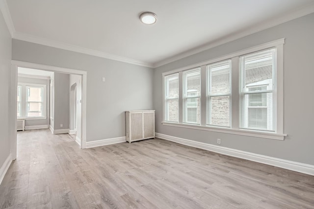 spare room with light wood-type flooring, crown molding, and baseboards