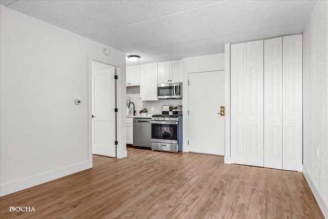 1750 N Marywood Ave Unit 501, Aurora, IL 60505 - kitchen featuring a sink, white cabinetry, decorative backsplash, light wood-style floors, and appliances with stainless steel finishes