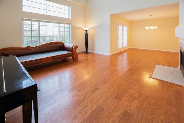 living area featuring light wood-style floors, a healthy amount of sunlight, baseboards, and a chandelier