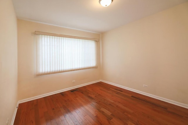 empty room with wood-type flooring, baseboards, and visible vents