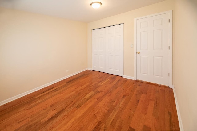 unfurnished bedroom featuring baseboards, a closet, and light wood-style flooring