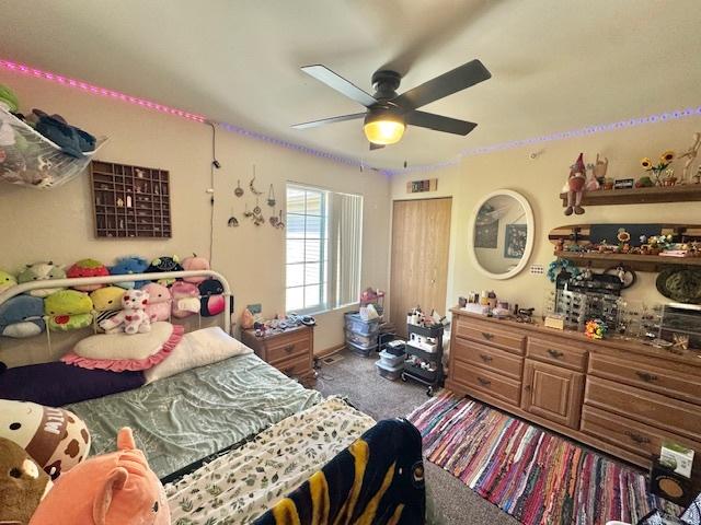 carpeted bedroom featuring visible vents, ceiling fan, and a closet