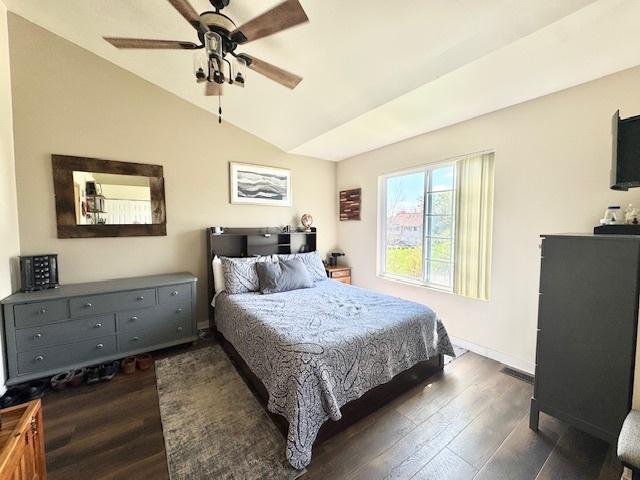 bedroom with ceiling fan, baseboards, vaulted ceiling, and dark wood finished floors