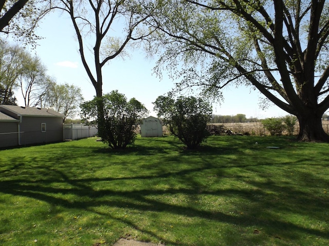 view of yard featuring an outdoor structure, a shed, and fence