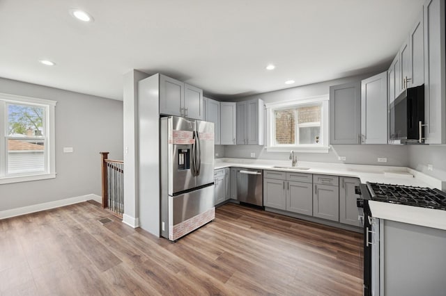 3141 Harvey Ave, Berwyn, IL 60402 - kitchen with gray cabinetry, appliances with stainless steel finishes, a sink, and wood finished floors