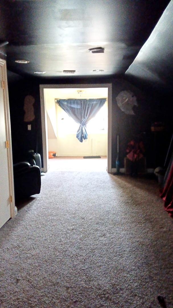 hallway with lofted ceiling, visible vents, and carpet floors