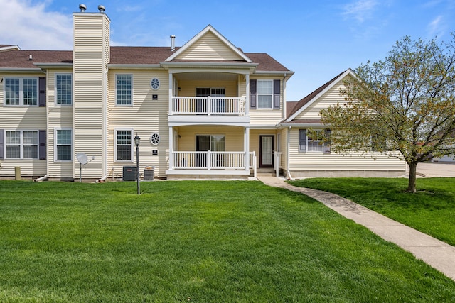 view of front of house featuring covered porch, a chimney, a front yard, and a balcony