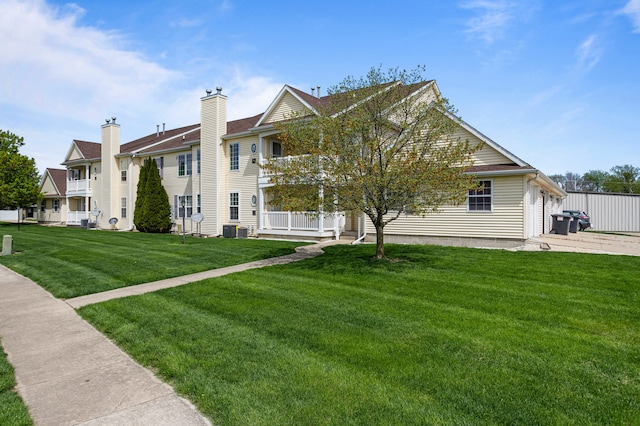 exterior space with an attached garage, central AC unit, and a front yard