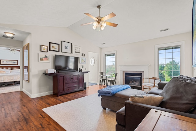living room with ceiling fan, visible vents, vaulted ceiling, and dark wood-type flooring