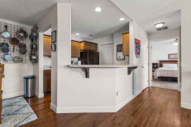 kitchen with baseboards, visible vents, dark wood-style floors, and black fridge with ice dispenser