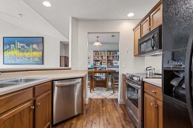 kitchen featuring dark wood finished floors, brown cabinets, light countertops, a sink, and black appliances