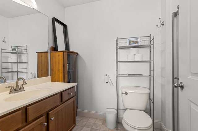 bathroom with baseboards, tile patterned floors, toilet, and vanity