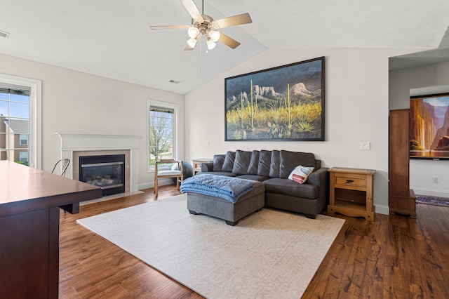 living area featuring vaulted ceiling, a ceiling fan, a fireplace with flush hearth, and wood finished floors