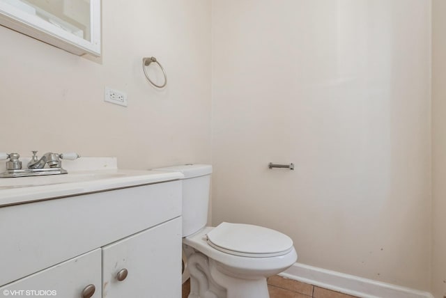 half bathroom featuring tile patterned floors, toilet, vanity, and baseboards
