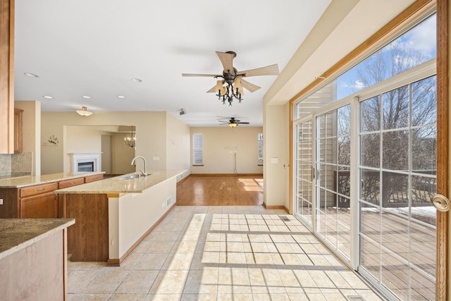 11253 Victoria Ln, Huntley, IL 60142 - kitchen featuring light stone countertops, brown cabinetry, a sink, a ceiling fan, and open floor plan