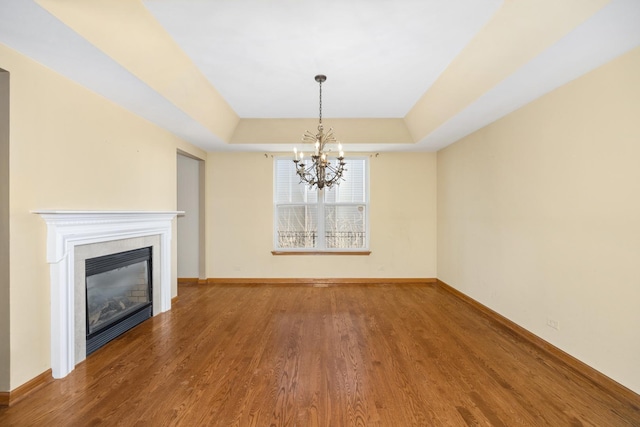 11253 Victoria Ln, Huntley, IL 60142 - unfurnished living room with baseboards, wood finished floors, a chandelier, and a tray ceiling