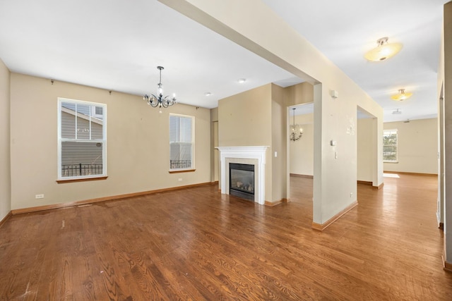 11253 Victoria Ln, Huntley, IL 60142 - unfurnished living room featuring wood finished floors, a chandelier, and baseboards