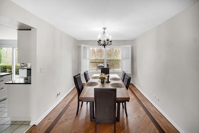 dining space with an inviting chandelier, wood finished floors, a healthy amount of sunlight, and baseboards