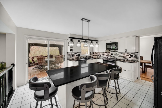 kitchen with a sink, light tile patterned flooring, tasteful backsplash, black appliances, and dark countertops