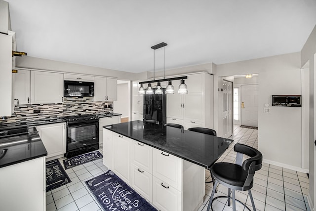 kitchen featuring light tile patterned floors, decorative backsplash, dark countertops, black appliances, and a kitchen bar