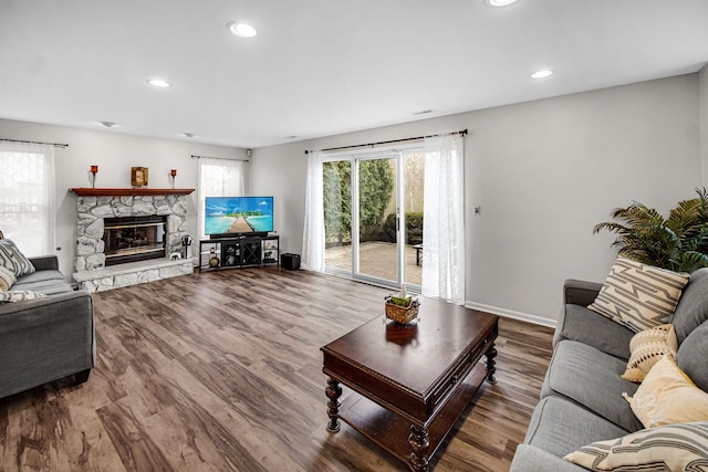 living area featuring baseboards, recessed lighting, wood finished floors, and a fireplace