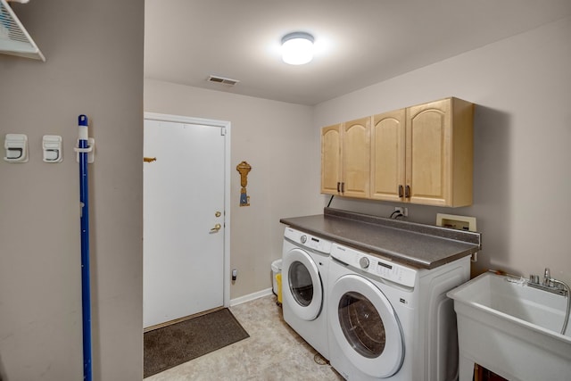 washroom with a sink, visible vents, baseboards, washer and dryer, and cabinet space