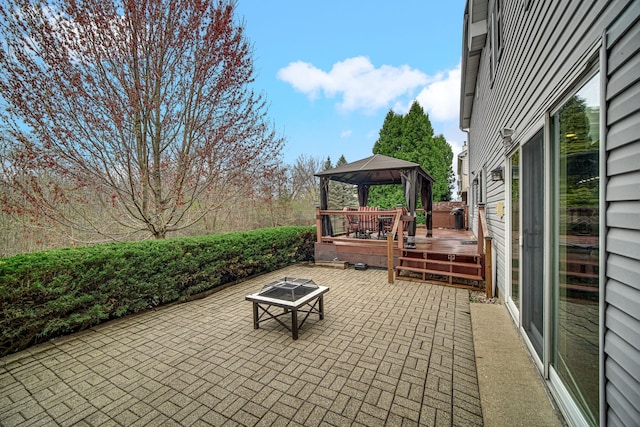 view of patio featuring a wooden deck, a gazebo, and a fire pit