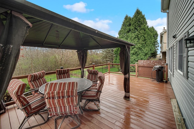wooden deck featuring outdoor dining space, area for grilling, and a gazebo