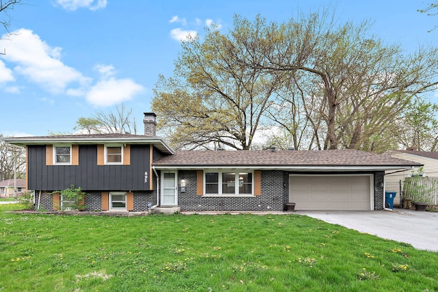 split level home with concrete driveway, a chimney, brick siding, a front lawn, and a garage