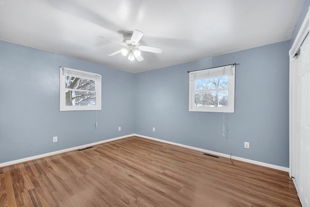 unfurnished bedroom featuring baseboards, visible vents, and multiple windows
